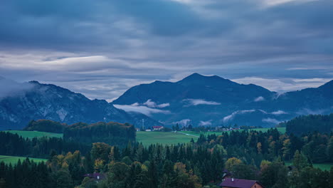 Morning-timelapse-of-foggy-Attersee-mountains,-village-cottages-with-mountain-range-in-the-background,-Austria
