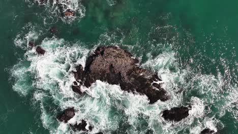 Top-View-Of-Foamy-Waves-Splashing-On-Rocks-In-The-Beach-In-Dana-Point,-California,-United-States---Drone-Shot