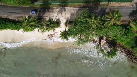 Drone-shot-of-climate-change,-global-warming,-high-tide-that-sea-level-rise-until-the-main-road,-passing-car-over-sand,-anse-royale-beach,-Mahe,-Seychelles-30fps-1