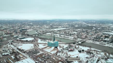 Establecimiento-De-Un-Amplio-ángulo-Frío-Disparo-Completo-Museo-Canadiense-De-Derechos-Humanos-Urbano-Winnipeg-Manitoba-Canadá-Centro-Rascacielos-Edificios-En-La-Ciudad-Paisaje-Nublado-Horizonte-Nevando-Invierno-Drone-4k-Tiro