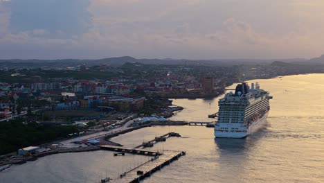 Golden-hour-light-spread-across-ocean-water-at-cinematic-Caribbean-port-town-with-cruise-ship