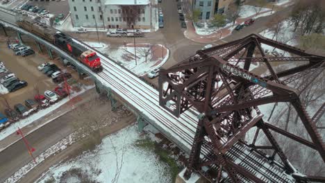 A-4K-Wide-Aerial-Drone-Clip-of-a-Large-Industrial-Coal-Power-Transport-CN-Rail-Train-Locomotive-Driving-Down-Tracks-Through-Steel-River-Crossing-Bridge-in-Winter-Winnipeg-Manitoba-Canada