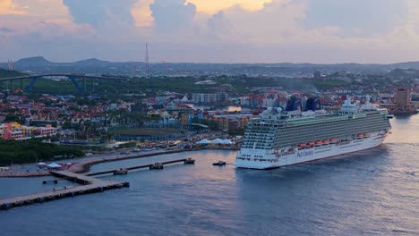 Wide-angle-aerial-of-large-cruise-ship-liner-docked-at-harbor-in-Caribbean