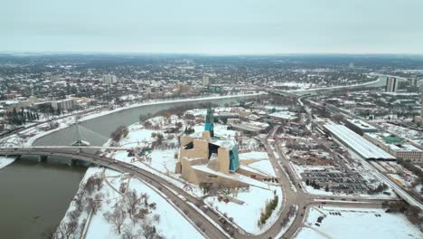 Gründungsaufnahme-Kanadisches-Museum-Für-Menschenrechte-Urban-Winnipeg-Manitoba-Kanada-Innenstadt-Wolkenkratzer-Gebäude-In-Der-Stadt-Bewölkte-Landschaft-Skyline-Schneit-Winter-Drohne-4K-Aufnahme-Langsam-Filmisch