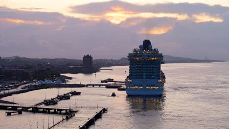 Drone-trucking-pan-across-harbor-for-large-cruise-ship-at-sunset