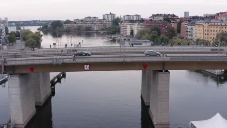 Cars,-cyclists-and-pedestrians-going-over-canal-on-Liljeholmsbron-bridge-in-Södermalm,-Stockholm,-Sweden-during-cloudy-evening