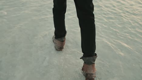 Follow-cam-of-man-wearing-jeans-and-leather-boots-walking-in-ankle-deep-water