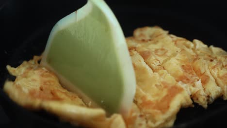 Eine-Knusprige-Nahaufnahme,-Wie-Das-Omelett-In-Einer-Schwarzen,-Heißen-Pfanne-Gewendet-Wird,-Ein-Ei-Mit-Ognion-Omelette,-Ein-4K-Frühstücksvideo
