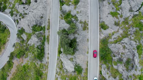 Cars-and-bikes-on-road-through-green-forested-mountain-range,-drone-aerial-view