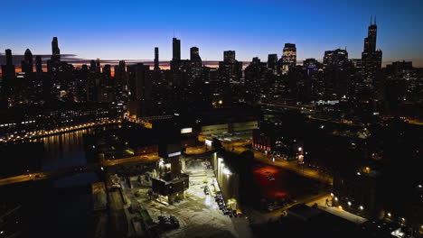 Aerial-view-rising-in-front-of-the-illuminated-Ozinga-Concrete-with-Chicago-skyline-background