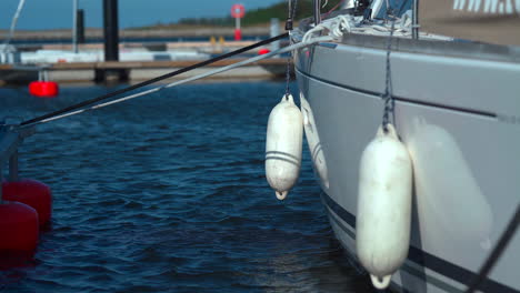 Closeup-shot-of-fenders-hanging-on-the-side-of-the-yacht-moored-in-the-marina-at-sunny-day