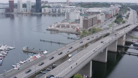 Traffic-going-over-canal-on-bridge-in-Södermalm,-Stockholm,-Sweden-during-cloudy-evening