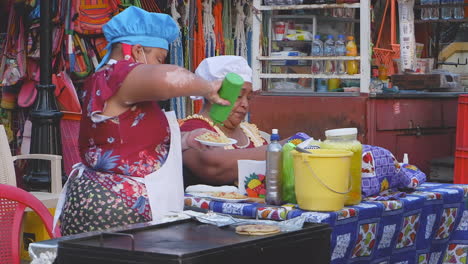 Two-women-provide-tasty-street-food-at-grill-cart-in-Leon,-Nicaragua
