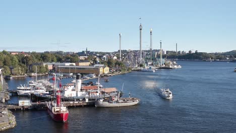 Barcos-En-El-Muelle-Y-Crucero-Con-Gröna-Lund-Al-Fondo-Durante-La-Tarde-Soleada-En-Djurgården,-Estocolmo,-Suecia