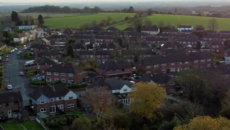 Small-British-town-property-neighbourhood-on-the-edge-of-rural-agricultural-farmland-at-sunset-aerial-view