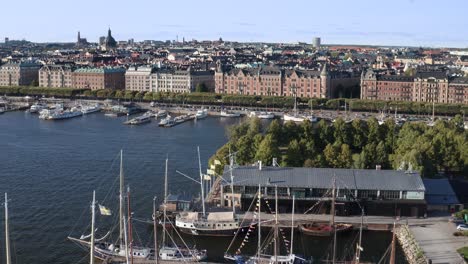 Sailboats-in-dock-with-city-skyline-in-background-during-sunny-evening-in-Djurgården,-Stockholm,-Sweden