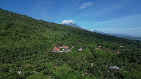 The-peak-of-Mount-Agung-volcano-in-Bali-with-jungle-greenery-in-the-foreground,-aerial