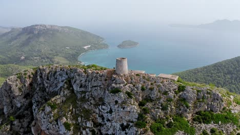 Old-ruined-tower-on-the-tip-of-an-island-Mountain-landscape-surrounded-by-a-blue-ocean