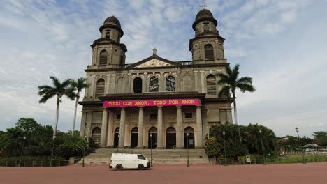 Small-van-drives-up-to-front-facade-of-Old-Cathedral-in-Managua,-NIC