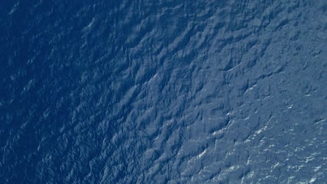 Drone-rises-from-ocean-surface,-a-mysterious-shade-of-deep-blue