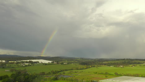 Die-Luftperspektive-Schwenkt-Sanft-Nach-Rechts-Und-Zeigt-Eine-Malerische-Naturlandschaft-Unter-Einem-Leuchtenden-Regenbogen