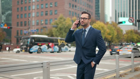 Happy-Businessman-Talking-on-Phone-Standing-By-Office-Building,-Reporting-Good-News