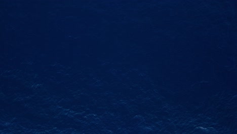 Dark-blue-pulsing-ocean-water-currents-background-texture,-bird's-eye-view