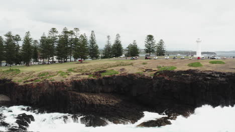 Aerial-drone-shot-around-Kiama-headland-to-reveal-the-Blow-hole,-on-a-stormy-day-in-south-coast-New-South-Wales,-Australia