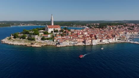 Aerial-view-as-a-boat-is-leaving-the-old-town-of-Rovinj,-famous-medieval-Croatian-city-at-the-sea