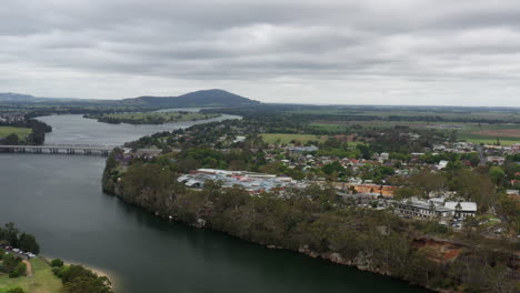 Arial-drone-shot-pulling-backwards-revealing-more-of-Nowra-on-a-stormy-day-next-to-the-Shoalhaven-river,-south-coast-NSW-Australia