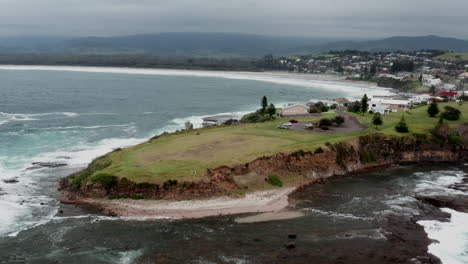 Aerial-drone-shot-tracking-left-around-Gerroa-headland-to-reveal-more-of-the-town-on-stormy-day-in-south-coast,-NSW,-Australia