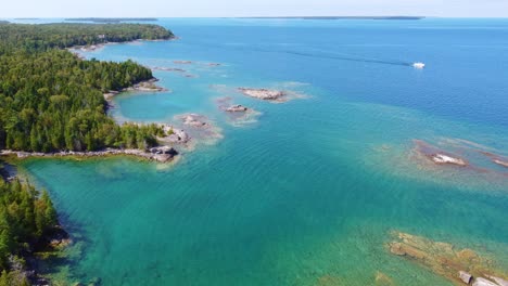 Drone-shot-moving-slowly-towards-the-left-over-a-dense-lush-boreal-forest-and-Georgian-Bay,-Ontario,-Canada