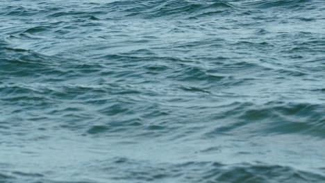 Close-up-of-the-sea's-surface-showing-subtle-ripples-and-the-reflections-of-the-sky
