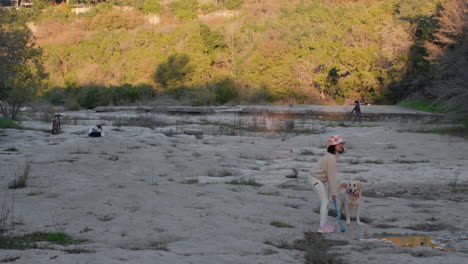Female-Asian-dog-throwing-ball-in-an-empty-riverbed-at-sunset