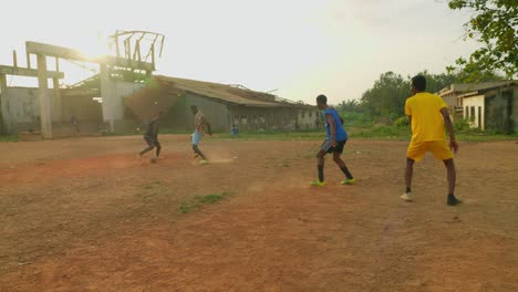 Passing-the-ball-to-the-one-with-a-yellow-shirt-then-passes-back-as-they-try-to-go-through-defenders,-young-people-playing-football-at-a-community-field-in-Kumasi,-Ghana