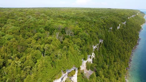 Drone-tilting-slowly-to-show-the-vast-expanse-of-the-Georgian-Bay-boreal-forest-and-coastline-in-Ontario,-Canada