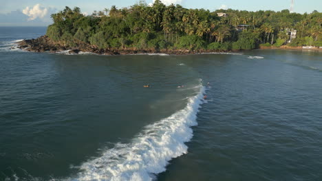 Establecimiento-De-Una-Toma-Aérea-De-Drones-De-2-Surfistas-Caucásicos,-Hombres-Y-Mujeres,-Montando-Una-Ola-Rompiendo-En-La-Costa-Sur-Tropical-De-Sri-Lanka,-Hiriketiya.