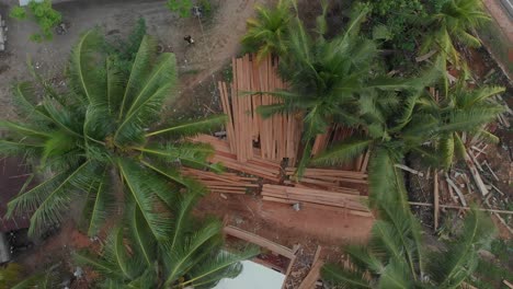 Rising-shot-of-man-sanding-wooden-planks-at-boat-construction-at-Belitung,-aerial