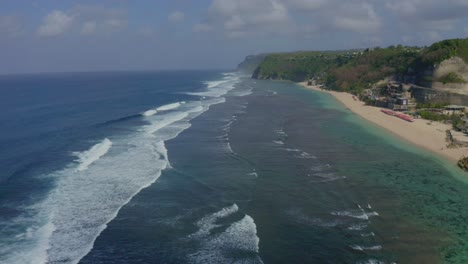 Melasti-bali-beach-AERIAL-drone-view-Drone-is-moving-forward,-and-waves-are-coming-in-the-water