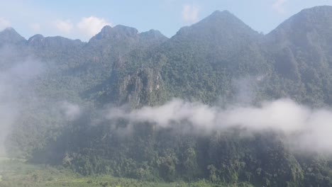 Vista-Aérea-Del-Paisaje-Nublado-En-El-Valle-Entre-Las-Montañas-Boscosas-De-Vang-Vieng