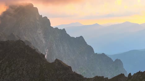 Riesige-Berglandschaft,-Dynamische,-Langsame,-Stabile-Drohnenaufnahme-Bei-Sonnenuntergang-In-Alpiner-Umgebung-Mit-Orangefarbenen-Und-Rosa-Wolken