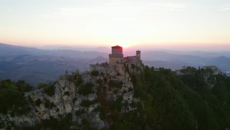 Three-towers-of-San-Marino,-Italy,-drone-pull-out-view-during-sunset