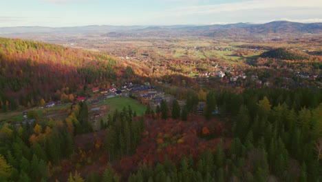 Karpacz,-Poland,-autumn-drone-tilt-up-view-of-a-mountain-city-well-lit