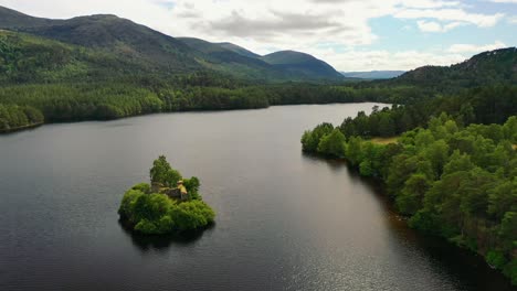 Above-the-Pines:-Loch-An-Eilein-and-Castle's-Aerial-Spectacle,-Nestled-in-Aviemore's-Scots-Pine-Forest,-Scottish-Highlands,-UK