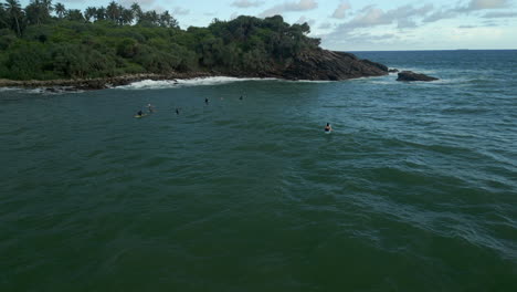 Static-Aerial-Drone-Shot-of-Surfers-Bobbing-and-Floating-in-the-Water-with-Small-Waves-in-Southern-Sri-Lanka-Hiriketiya