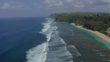 Wunderschöne-Aufnahme-Am-Strand-Von-Melasti-Auf-Bali.-Drohne-Bewegt-Sich-Vorwärts,-Wasserwellen-Erreichen-Das-Ufer-Des-Strandes
