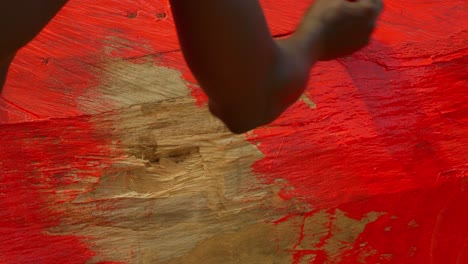 extreme-close-up-of-black-male-workers-painting-in-red-a-wooden-wall