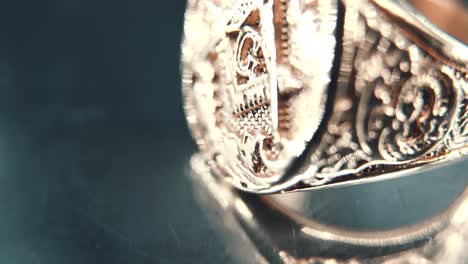 A-macro-detailed-tilt-up-shot-of-a-golden-textured-freemasons-ring,-on-a-rotating-stand,-mirror-reflection,-illuminati-symbol,-professional-studio-lighting,-4K-video