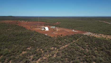 Aerial-approaching-shot-of-small-mine-site-in-Western-Australia-surrounded-by-green-countryside-fields-in-summer