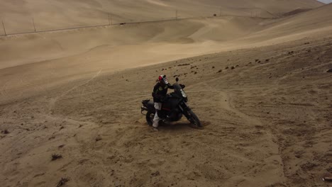 Motorcycle-stuck-in-the-sand-at-the-top-of-a-steep-hill-or-dune-in-the-desert